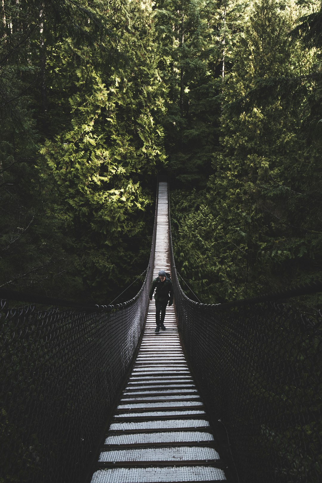 Photo by Liam Simpson photo of man walking of foot bridge